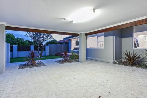 Paved rear courtyard under the alfresco roof, planted along the boundary