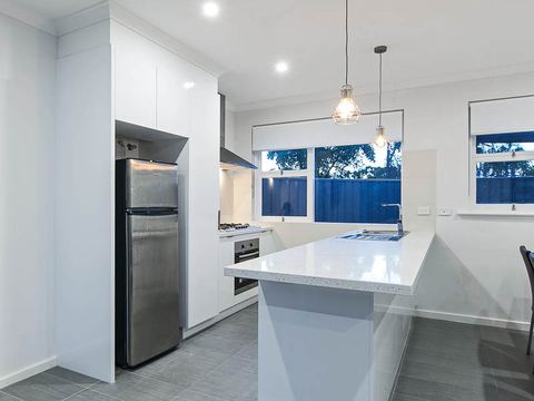 Kitchen with pendant lights over the island and windows above the benchtop