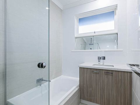 Bathroom with a bath alongside a glazed shower and a timber vanity