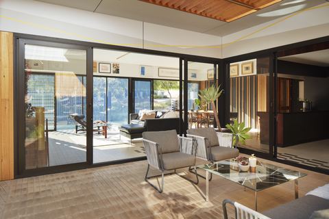 Living room opening through full-height sliding glazing onto a shaded terrace