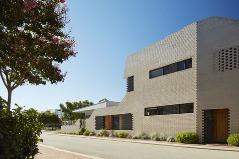 Street elevation in pale brick, with a perforated brick screen and deep-set windows