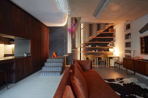 Living area with a dark timber wall, tiled stair and joinery running the length of the room