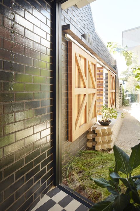 Side courtyard between a glazed black brick wall and a timber gate