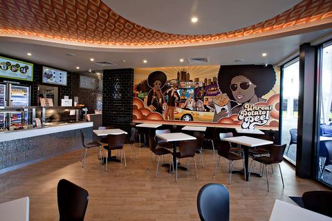 Dining room with a disco-themed wall mural, timber-look flooring and a patterned curved ceiling running above the counter