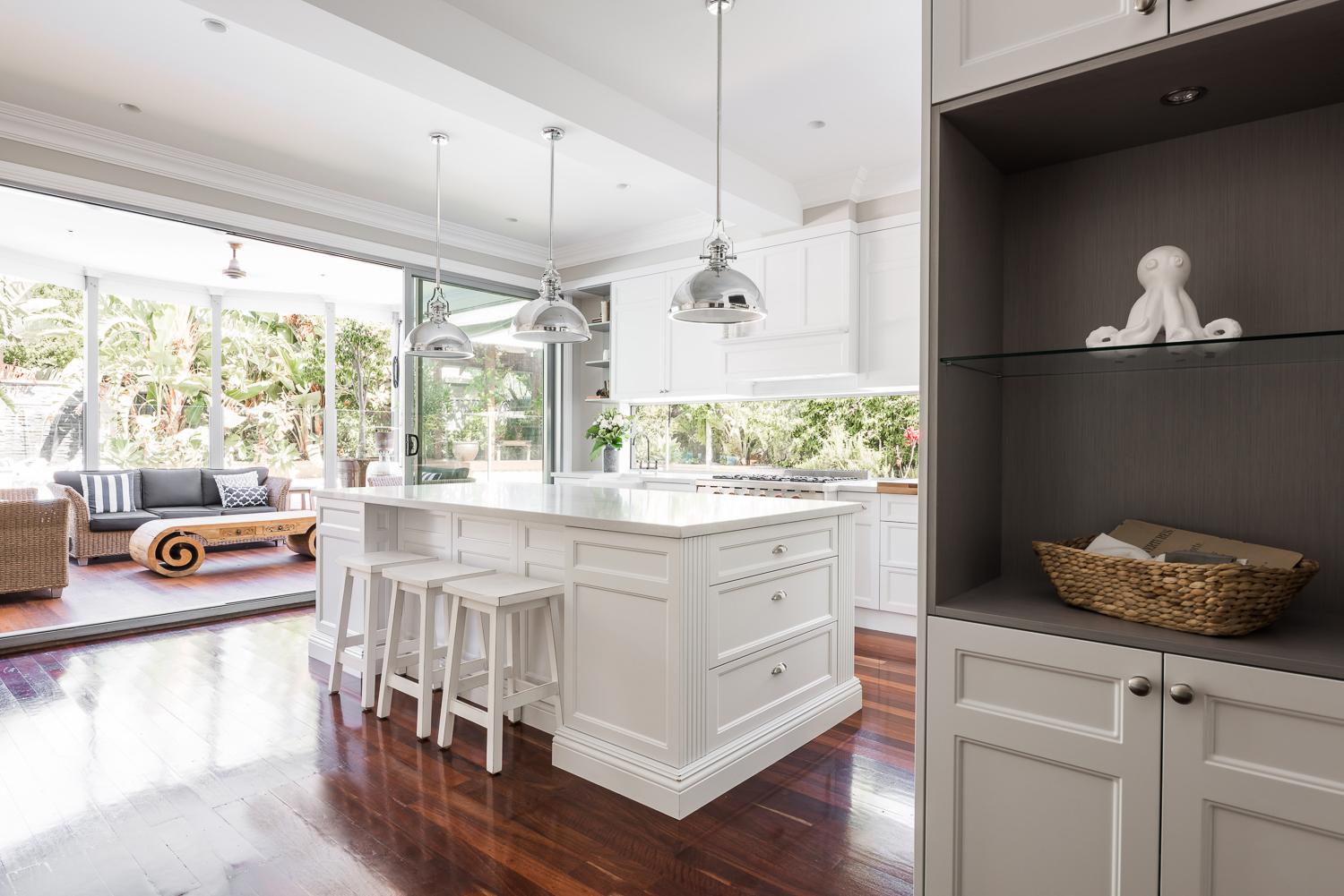 Kitchen looking through to a sunroom, with a large island and jarrah floors