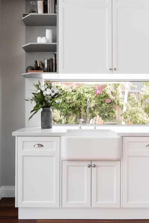 Cabinetry detail with open shelving above a farmhouse sink and a garden window