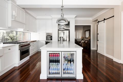 Kitchen with a glazed drinks fridge in the island and a barn door to the hall