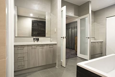 Bathroom with a twin vanity, mirrored cabinetry and a bath beyond
