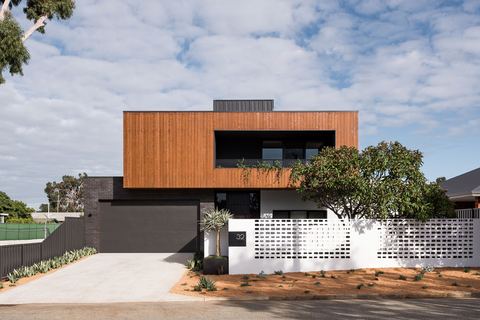 Two-storey street elevation, timber-clad above a rendered base, behind a white breeze-block screen wall