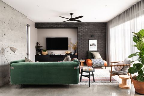 Living room with black brick wall, polished concrete floor and full-height sheer curtains