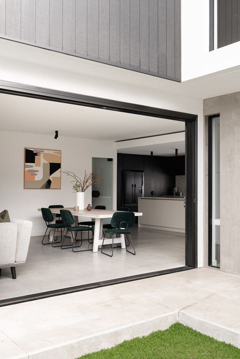 Living and dining space opening through wide sliding doors onto the lawn