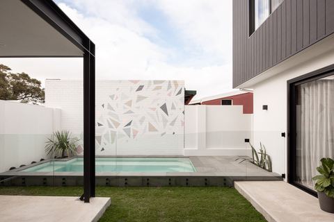 Plunge pool and terrace, with a patterned terrazzo wall panel behind the glass fence