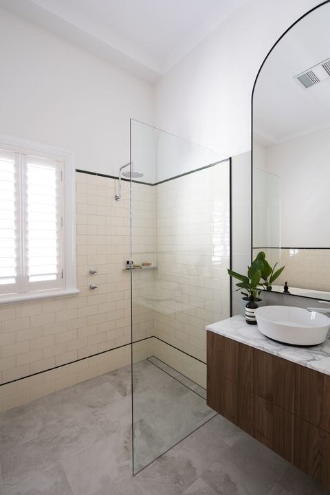 Bathroom with an arched mirror, timber vanity and marble benchtop