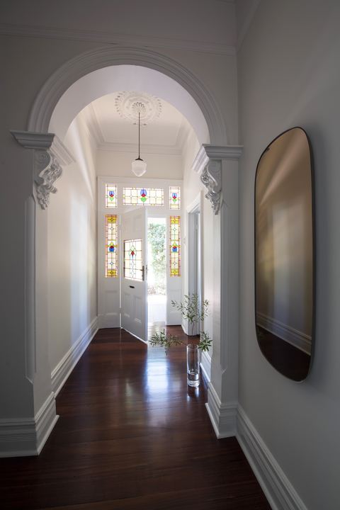 Hallway through an ornate arch to a leadlight front door